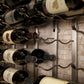 Wall-mounted wine rack with wine bottles on curved metal pegs