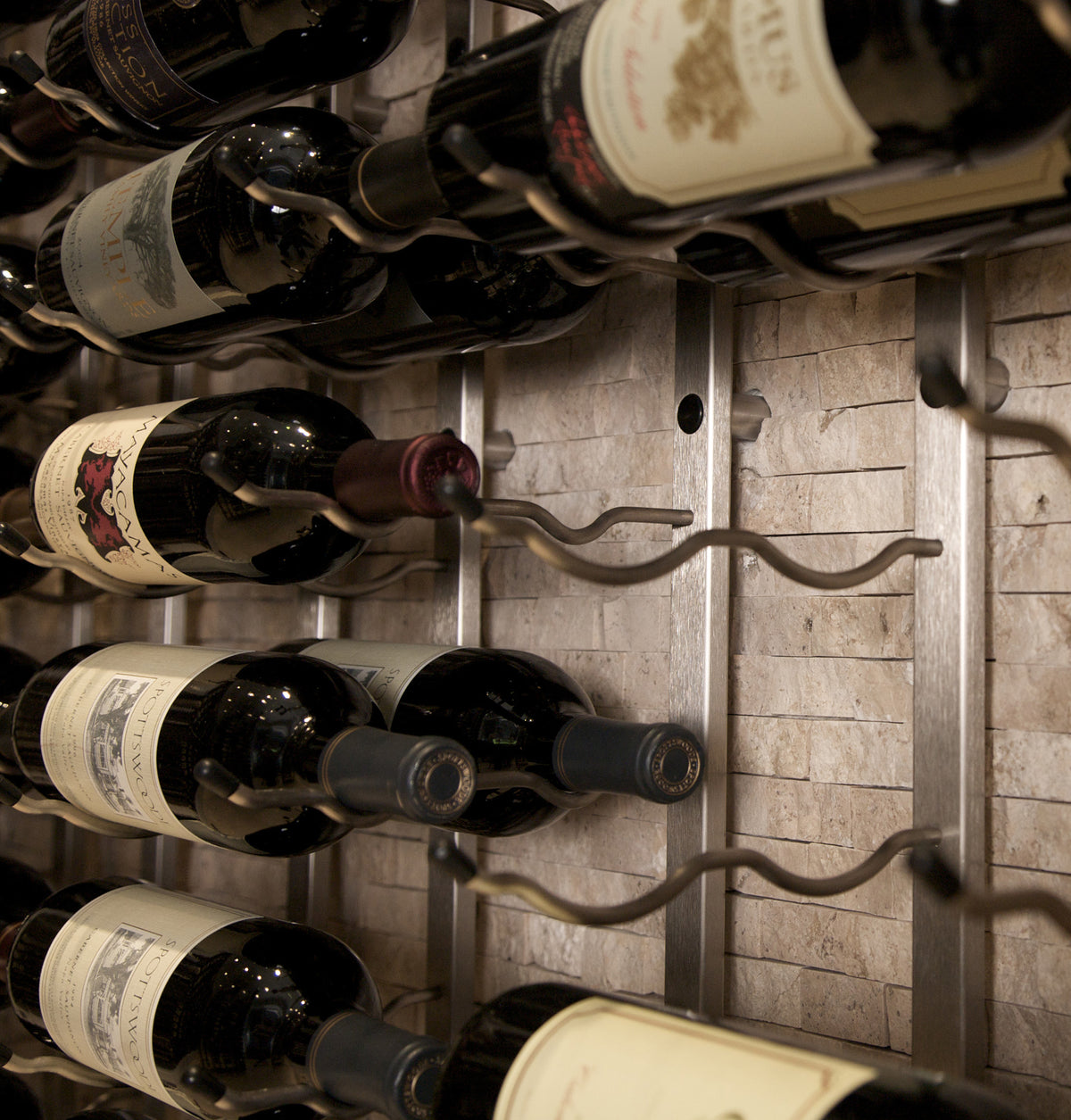 Wall-mounted wine rack with wine bottles on curved metal pegs
