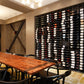 Wall wine rack with black frame holding rows of wine bottles indoors