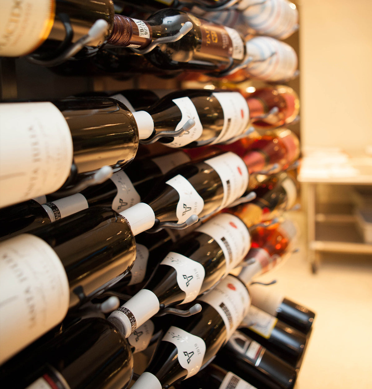Wine bottle display in wall-mounted rack with multiple bottles, close-up