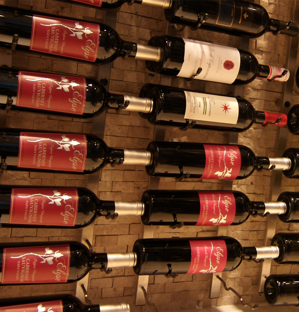 Wall-mounted wine rack holding red and white wine bottles, close-up on holders.