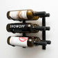 Wall-mounted wine rack with matte black frame holding three wine bottles