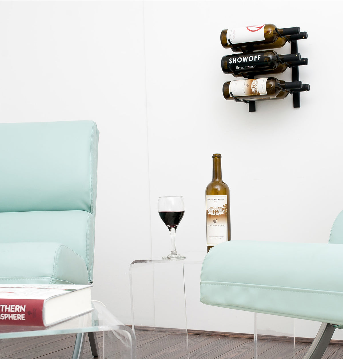 Wall wine rack with three bottle slots mounted above a glass and wine bottle