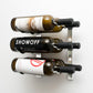 Wall-mounted wine rack with dark frame and metal bracket holding three wine bottles