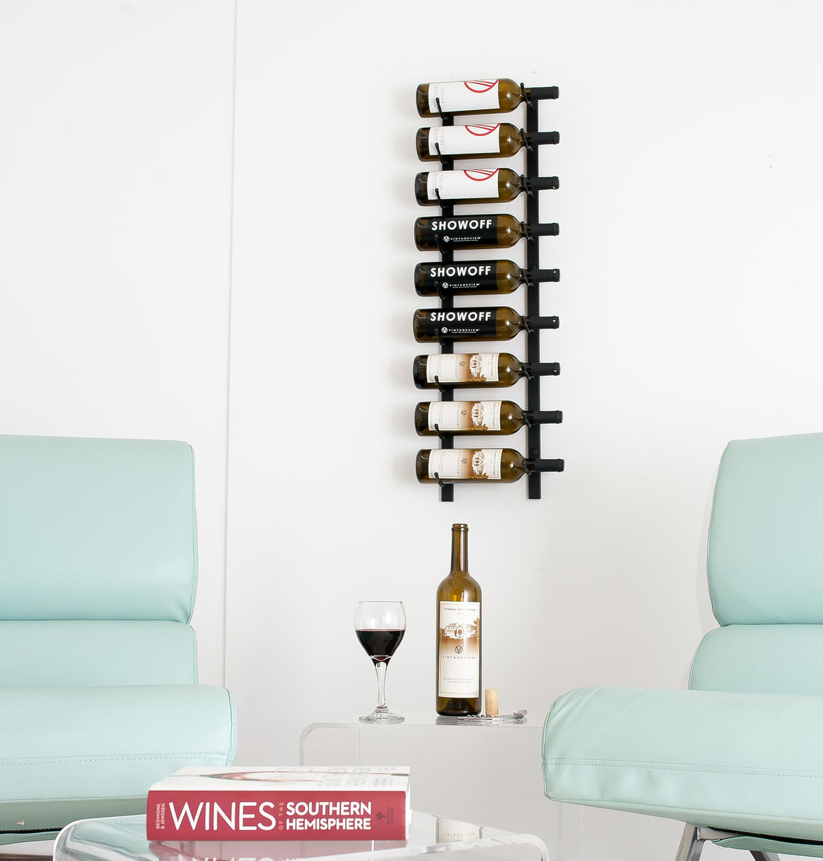 Wall-mounted wine rack with bottles above a table between two light blue chairs