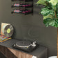 Black wall wine rack with three horizontal shelves holding bottles with colorful labels