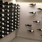 Wine bottle rack wall holding multiple dark wine bottles in a grid with black rails