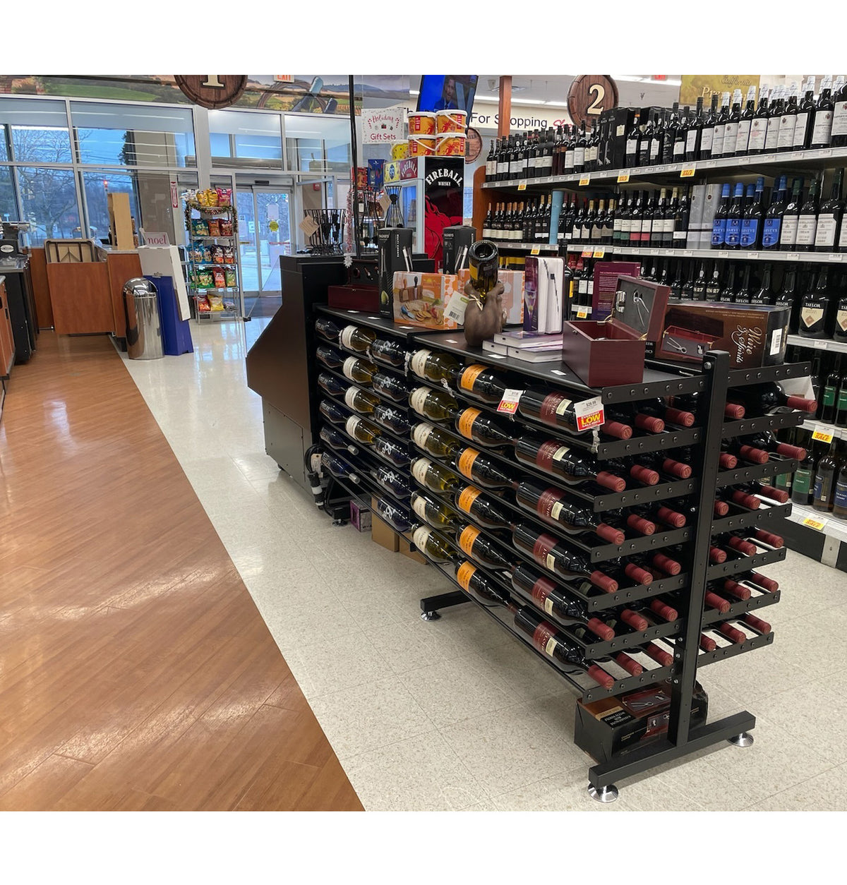 Double-sided wine bottle display rack with shelf, black metal, in-store bottle display on casters