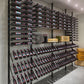 Large wall-mounted wine bottle rack display with rows of bottles and open shelving