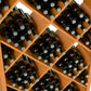 Close-up of wine bottles in diagonal diamond lattice slots of a wood bin