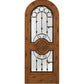 Honey-brown wood wine cellar door with arched iron speakeasy grille and decorative inset panels
