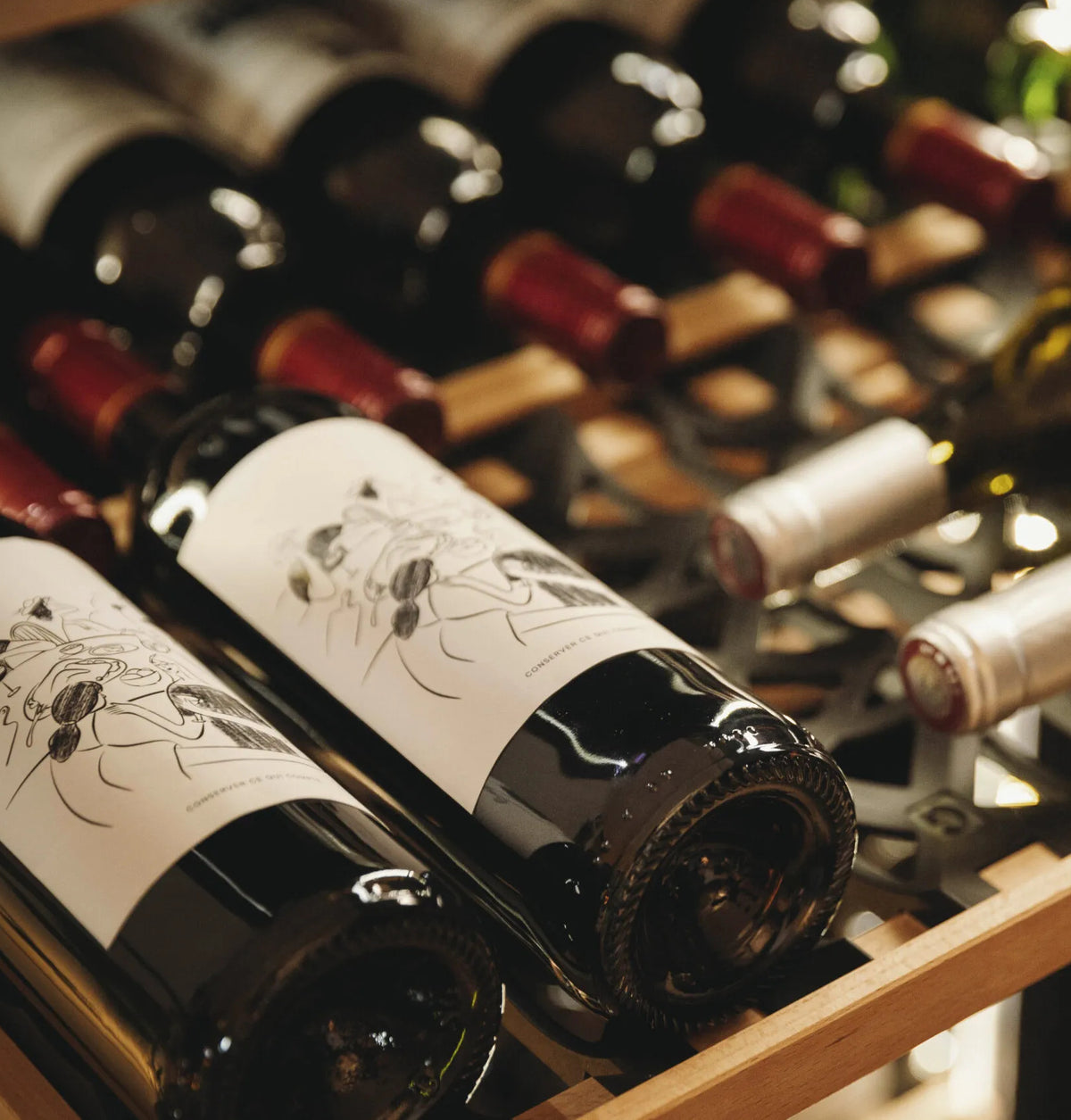 Wine bottles resting on wooden wine fridge shelves