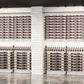 Double-sided wine bottle display rack with white finish and dense rows of bottle slots