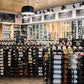Double-sided wine bottle display rack with black frame and multiple bottles per row.