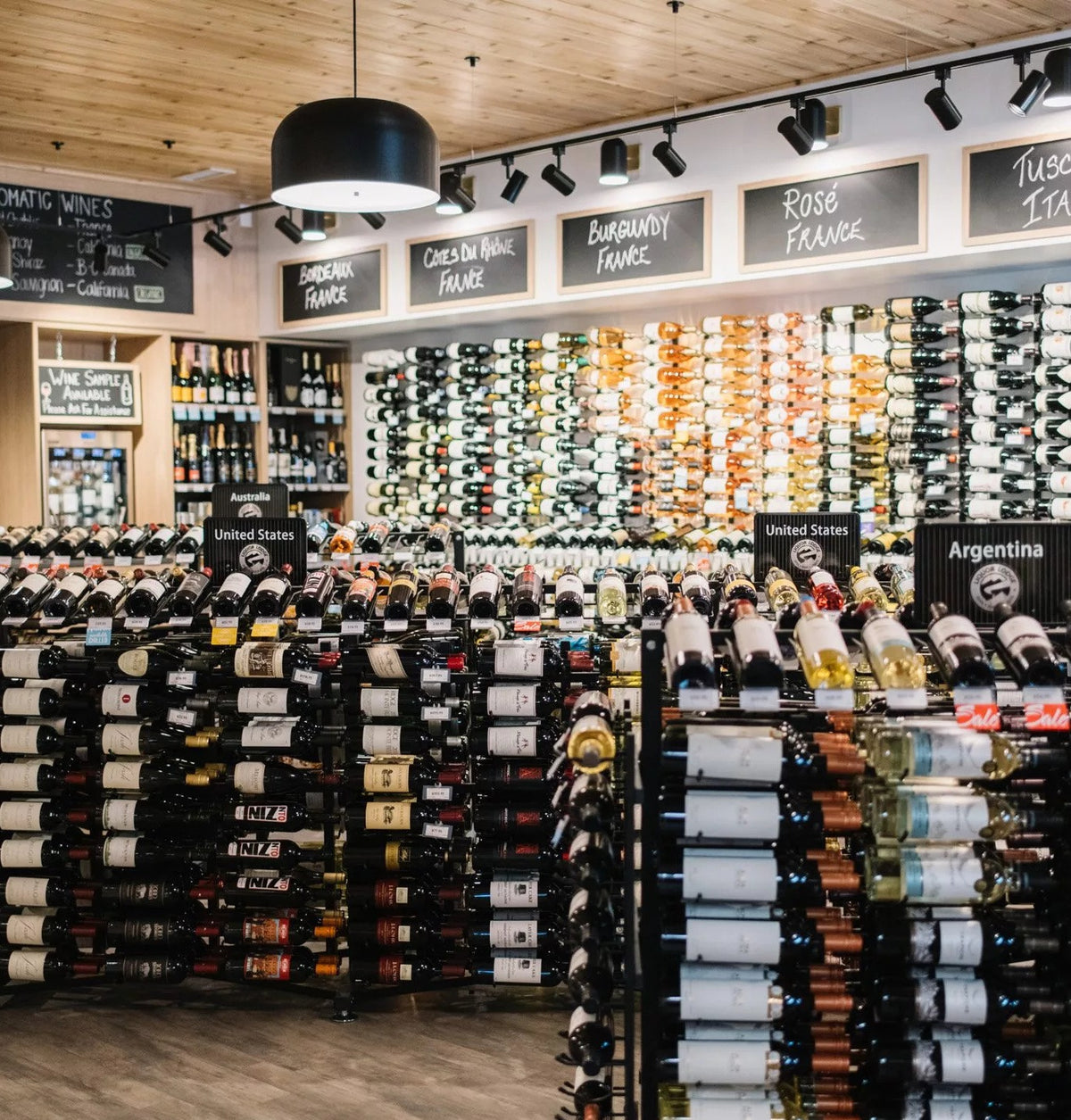 Double-sided wine bottle display rack with black frame and multiple bottles per row.