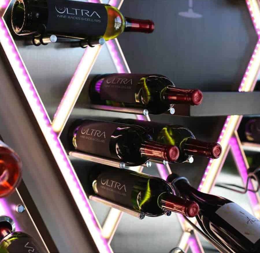 Cork-out wine peg system holding bottles on a lit wine rack, multiple bottles.