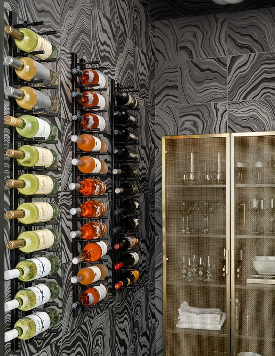 Wall wine peg rails with stacked bottles and black peg holders