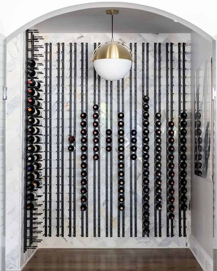 Black wine wall rack with many cork-out bottles on peg rails