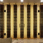 Wall-mounted wine bottle rack with black peg rows holding cork-topped bottles