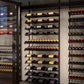 Wall-mounted wine bottle display rack with multiple horizontal shelves and bottle rows
