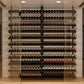 Wine bottle display rack wall with numerous tiers of assorted bottles behind glass