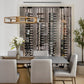 Wine bottle display wall with black peg racks and label-out bottles behind glass