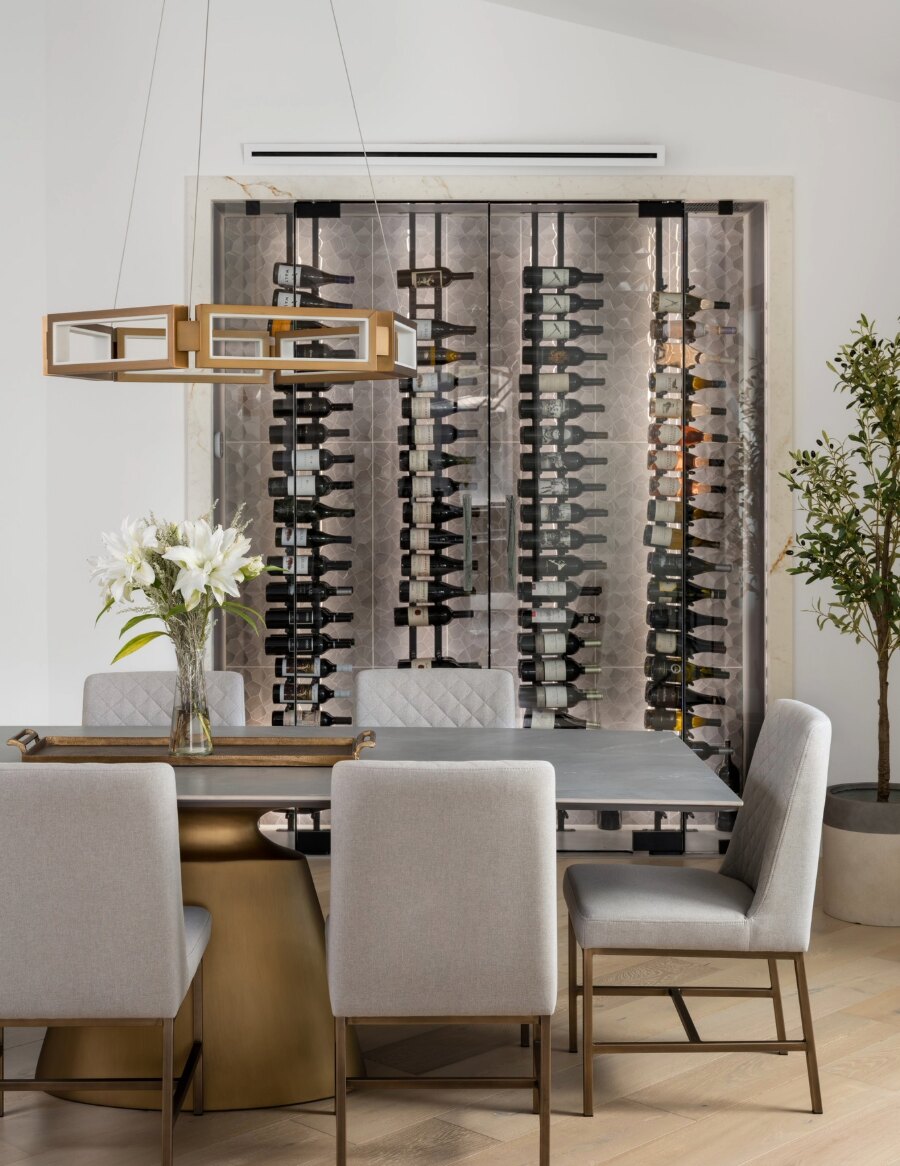 Wine bottle display wall with black peg racks and label-out bottles behind glass