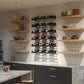 Wall-mounted cascading wine bottle display with multiple tiers of bottle slots