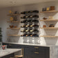 Wall wine bottle display with cascading shelves and bottle slots arranged in tiers