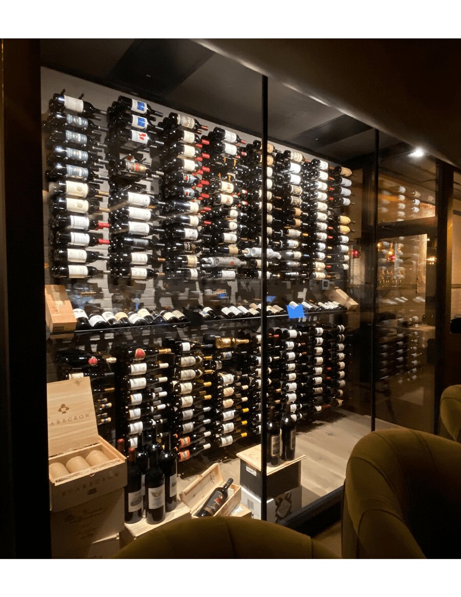 Interior wine wall with black label-out bottle display rows and many front-facing bottles