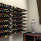 Wall-mounted wine bottle peg display with multiple bottles arranged in rows