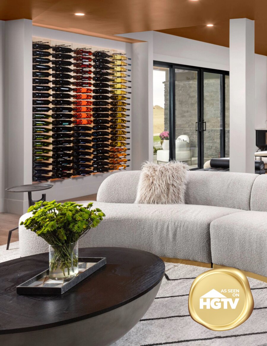 Aluminum wine bottle display wall with multi-colored bottles behind a modern sofa