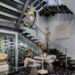 Aluminum wine bottle display wall with bottles next to a stairwell and dining area