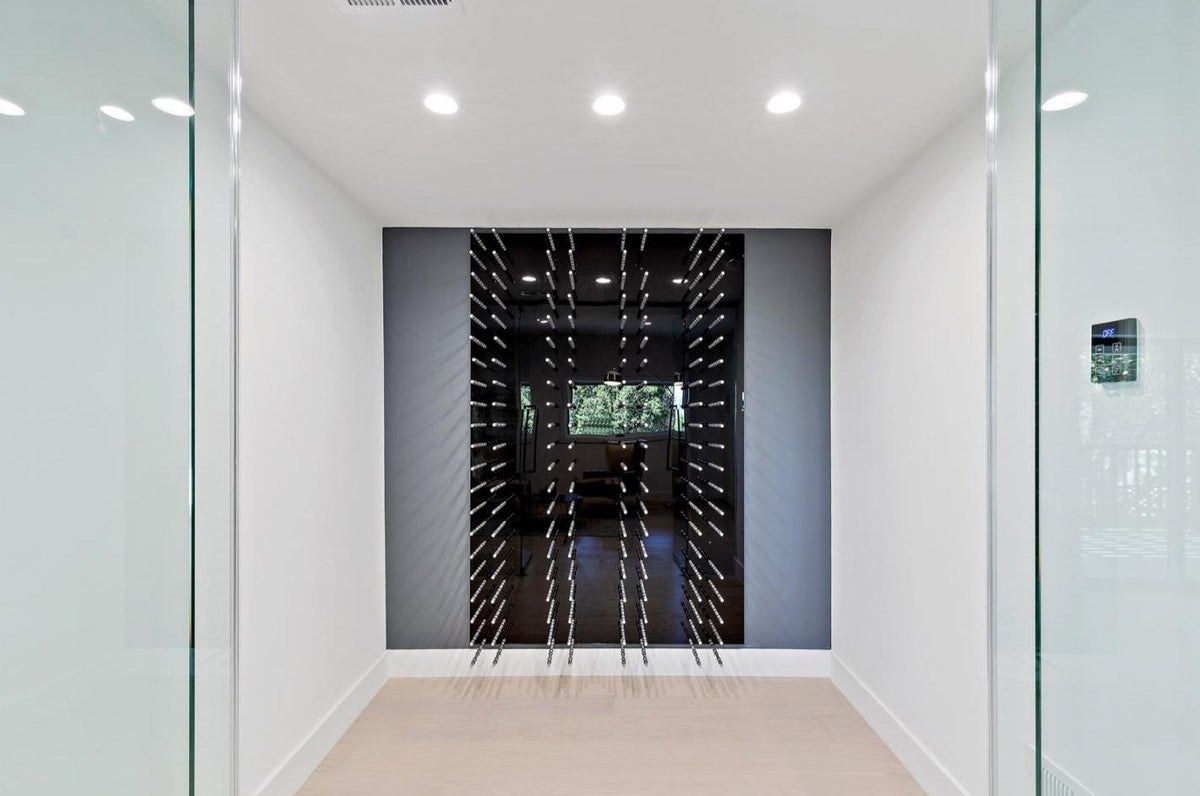 Black wine bottle wall rack with peg rails holding bottles in a built-in panel