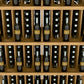 Wood wine bottle display with five shelves and rows of bottles in angled slots