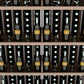 Close-up of wine bottles stored in a 5-shelf wall display rack with wooden dividers