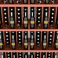 Close-up of wine bottle rows in a 5-shelf rack with red wood shelves
