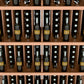 Close-up view of wine bottles in a 5-shelf wall display rack with light wood shelves