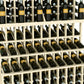 Triple-tier wine bottle display with light wood lattice shelves holding dark green bottles
