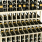 Triple-tier wine bottle display rack with light wood dividers holding wine bottles