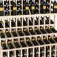 Triple-tier wine bottle display with light wood slats holding dark wine bottles