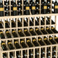 Triple-tier wine bottle display rack in light wood with three rows of bottle slots.
