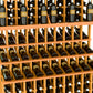 Wine bottle display rack detail with light amber slats holding bottles on three tiers