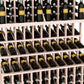 Wine bottle display rack detail with pale wood slats holding bottles on three tiers