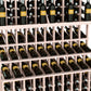 Triple-tier wine bottle display rack with whitewashed wood slats and bottle neck slots